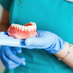 Врач-стоматолог держит в руке зубной протез