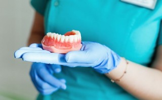 Врач-стоматолог держит в руке зубной протез