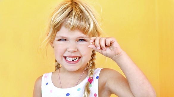 Фото девочка держит в руке удаленный зуб